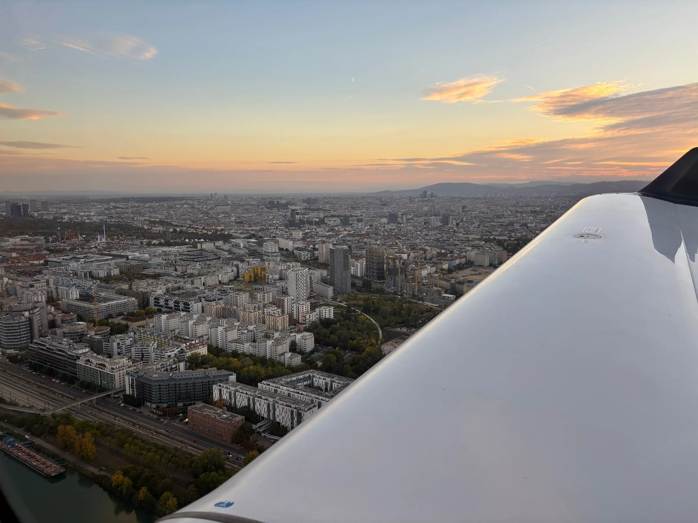 Vienna's streets and skyline seen over the wing in warm evening light